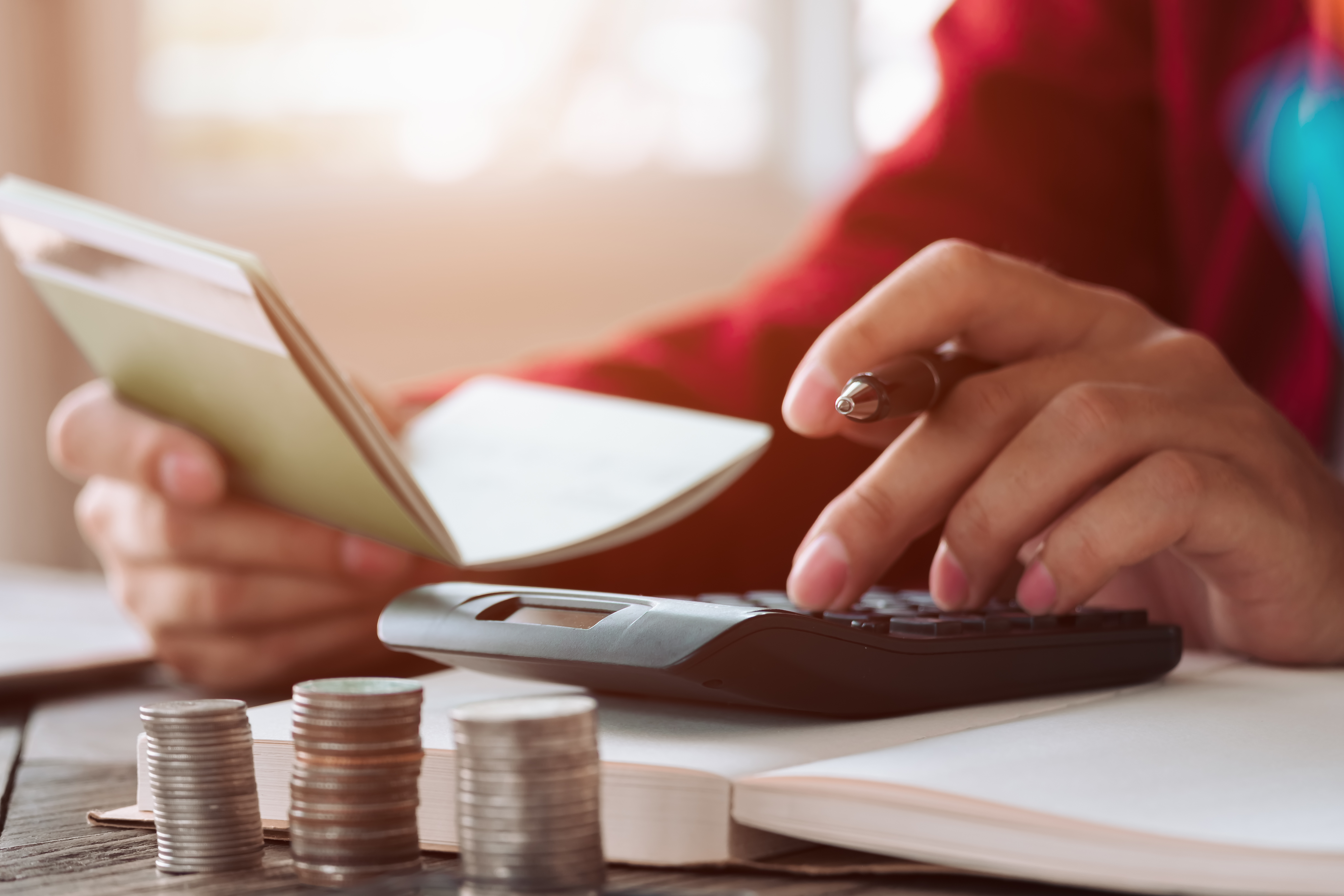 persona haciendo cuentas con una calculadora y una libreta